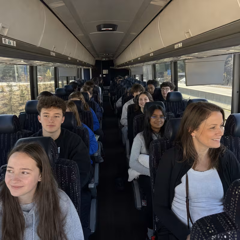 Group boarding a white charter bus for School Transportation transportation in Greensboro