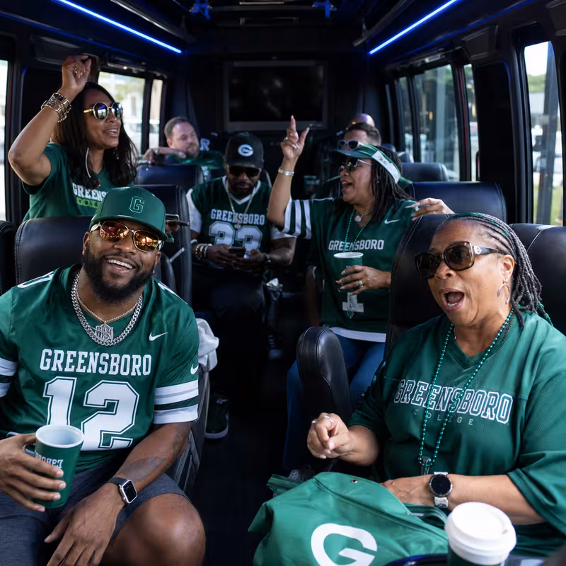 Group boarding a white charter bus for Sporting Event Transportation transportation in Greensboro